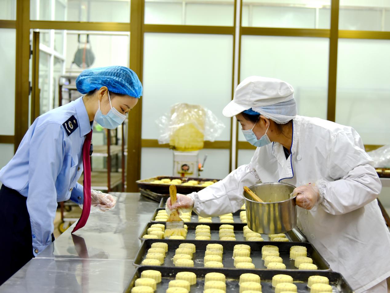 稅務干部走進月餅加工廠了解月餅生產(chǎn)過程。關卻吉攝