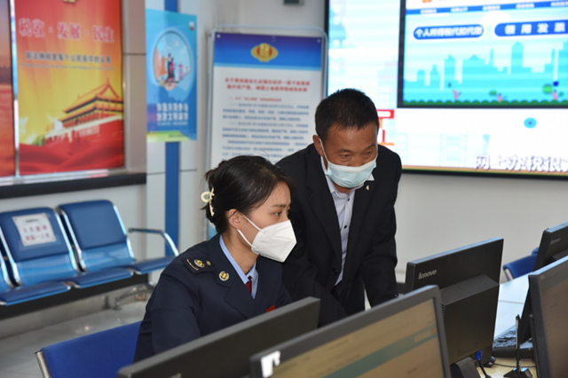 稅務(wù)人員輔導(dǎo)納稅人進(jìn)行備案登記。安迎春攝