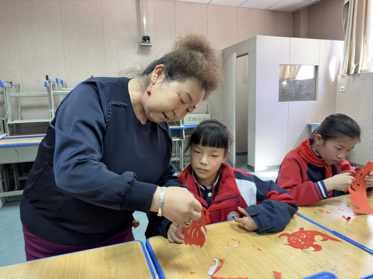 城北區(qū)非遺傳承人張風(fēng)蘭教授學(xué)生剪紙技藝。李昊攝