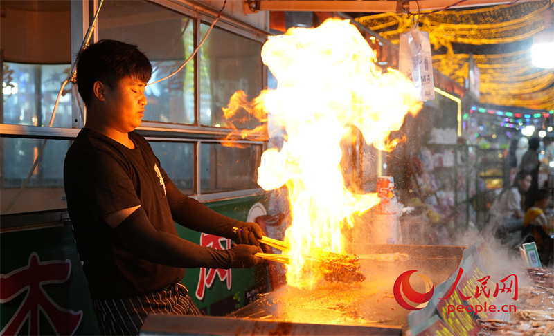 旱碼頭1960商業(yè)街內(nèi)火爆魷魚攤位的攤主正在忙活。人民網(wǎng)記者 甘海瓊攝