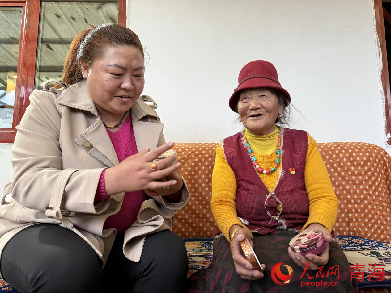 西毛(右)給索南吉展示在北京買到的紀(jì)念品。人民網(wǎng) 況玉攝