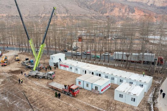 12月22日，在甘肅省臨夏州積石山縣劉集鄉(xiāng)陶家村，施工人員正在吊裝箱式房。人民網(wǎng)記者 翁奇羽攝